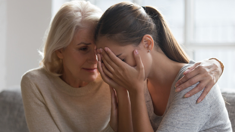 Woman cries as she is comforted by an elderly woman