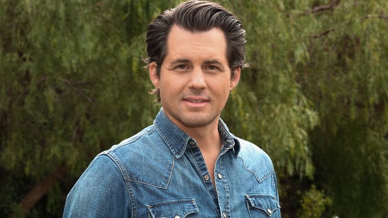 Hallmark star Kristoffer Polaha poses in front of a tree