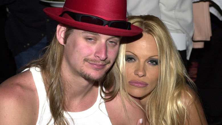 Kid Rock and Pamela Anderson snuggling up together at an event.