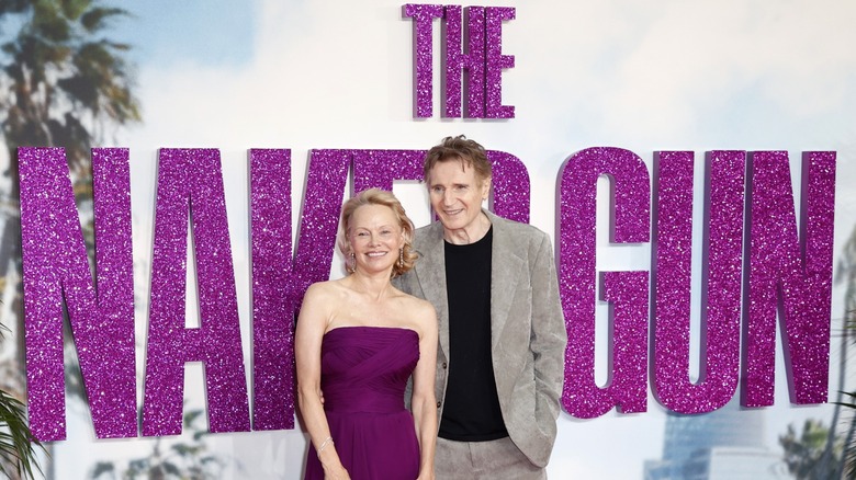 Pamela Anderson and Liam Neeson in front of a purple glittery step-and-repeat for The Naked Gun