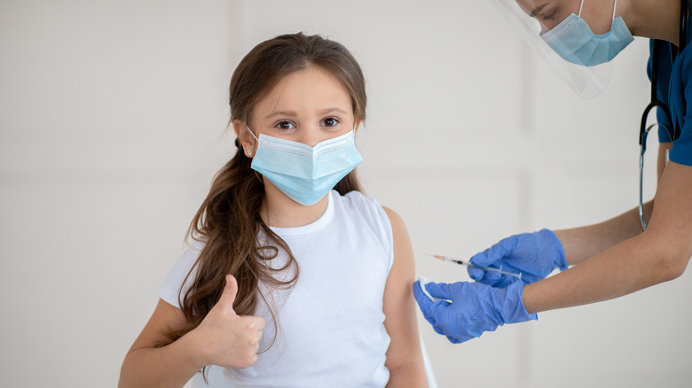 Girl wearing a face mask receiving a vaccine