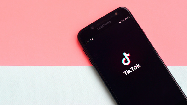 TikTok on phone on pink and white background
