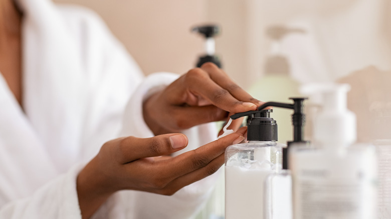 woman hands using cosmetic liquid soap in bathroom.