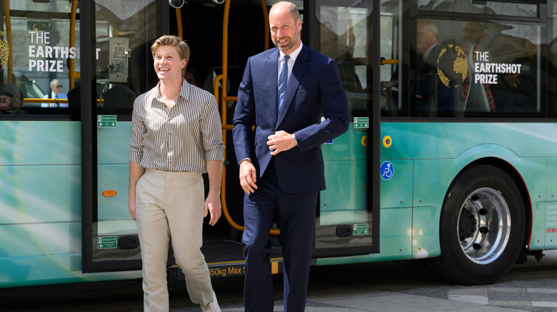 A smiling Prince William and Robert Irwin getting off an electric bus in London during Climate Action Week