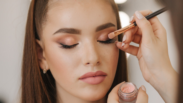 Young woman getting her makeup done by a professional artist 