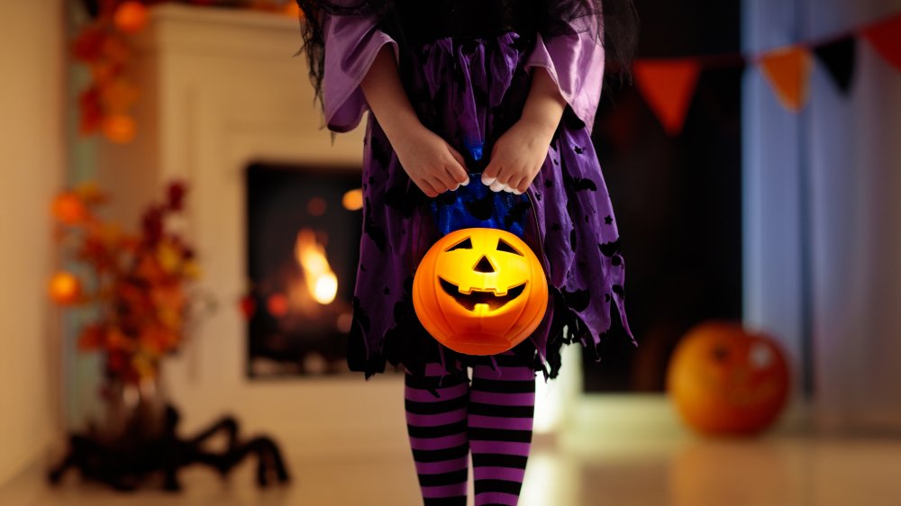 A child in a purple witch costume trick or treating