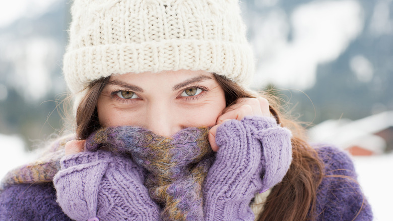 A woman wearing a purple winter scarf and white hat 