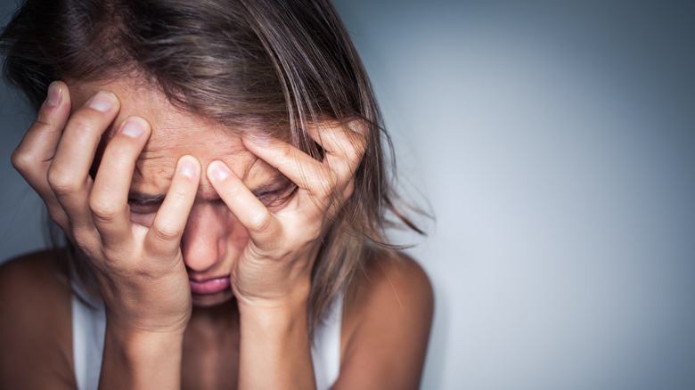 woman covering her face upset