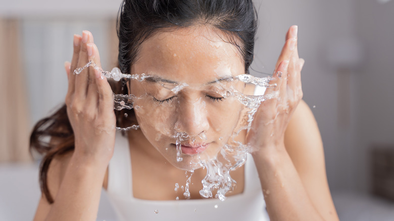 Woman washing face with water