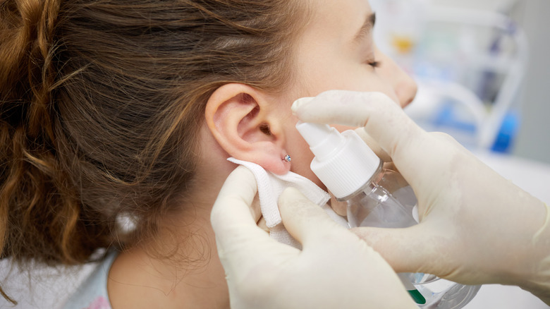 Girl sanitizing her ear piercing