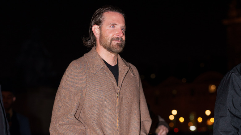 Bradley Cooper walking into an event in a brown jacket