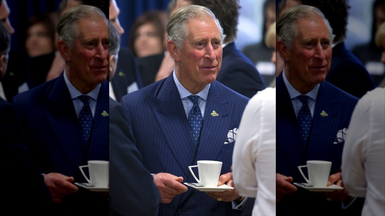 King Charles III engaged in conversation while holding a cup of tea