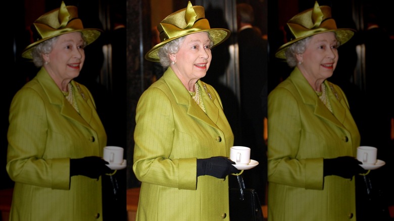 Queen Elizabeth II smiling while holding a cup of tea