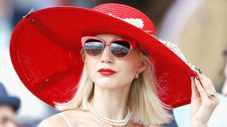 Blonde woman wearing big red hat at the Kentucky Derby