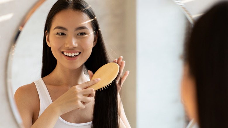 woman brushing long hair in mirror