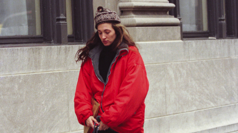Carolyn Bessette walking outside in hat and puffy coat
