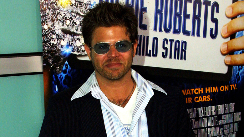 Adam Rich wearing sunglasses in front of a poster