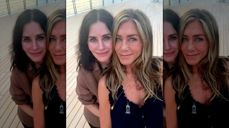 Courtney Cox leaning on Jennifer Aniston on a dock.