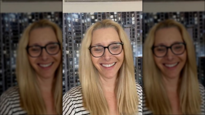 Lisa Kudrow in dark framed glasses and a striped shirt.