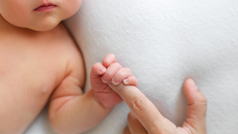 Baby gripping mom's finger
