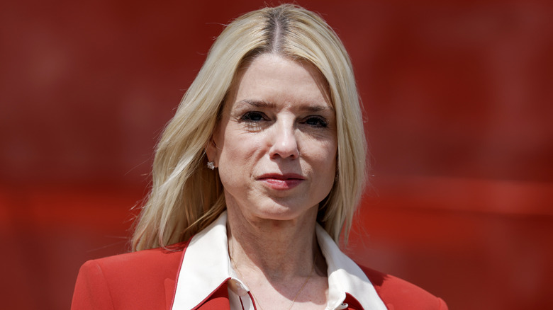 Pam Bondi stands in front of a red background