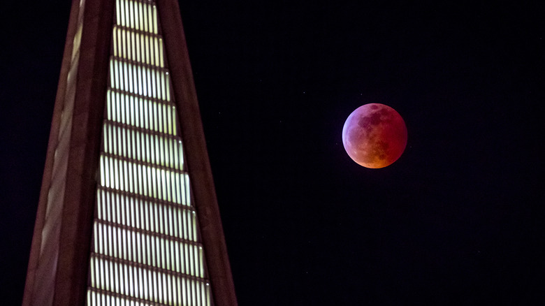 Red blood full moon next to building