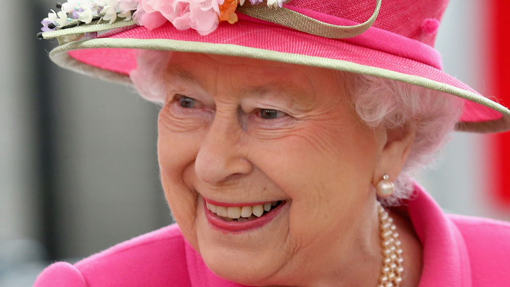 The Queen smiling in a pink hat