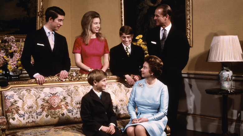 Queen Elizabeth and Prince Philip looking at and smiling with their four children: King Charles, Princess Anne, Prince Andrew, and Prince Edward