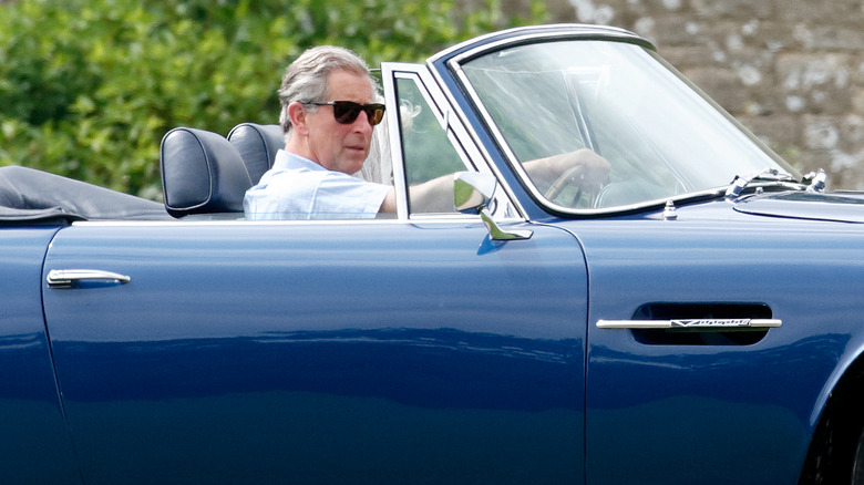 King Charles III driving while wearing sunglasses