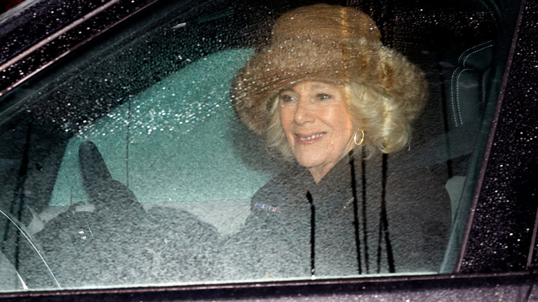 Queen Camilla driving while wearing a fluffy hat
