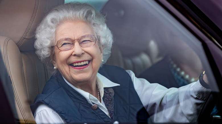 Queen Elizabeth II having a laugh behind the wheel of a car