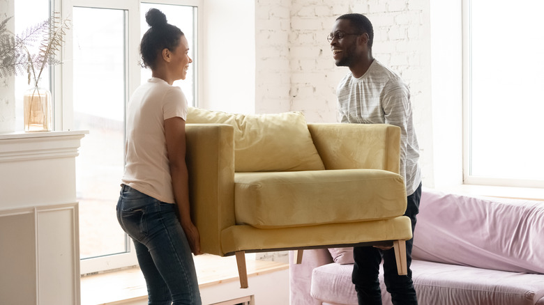 Two people move a chair. 