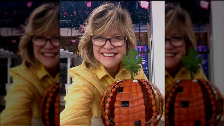 Carolyn Gracie smiles for a selfie with a pumpkin decor