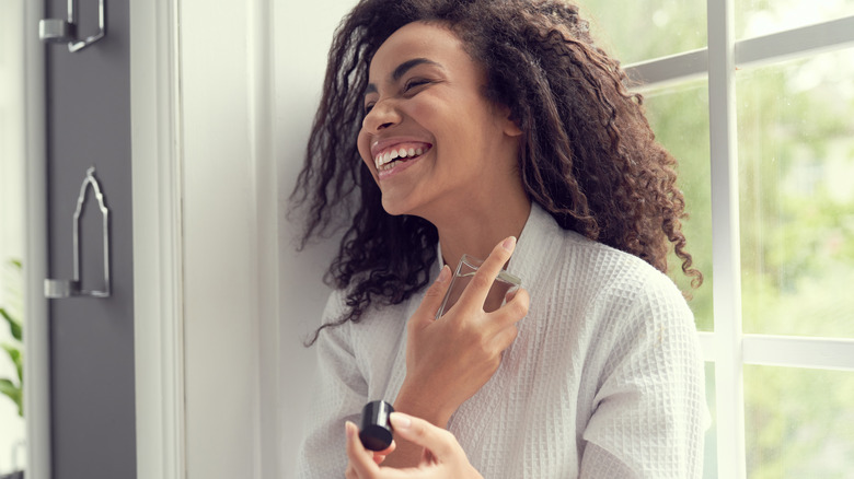 Woman spraying perfume on neck