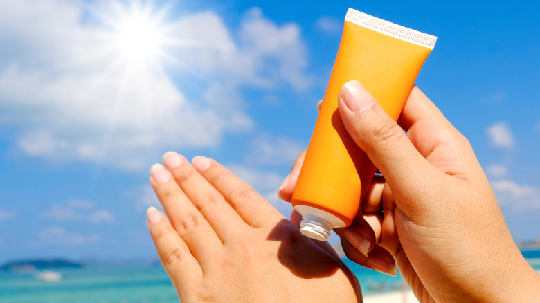 woman applying sunscreen lotion on hands
