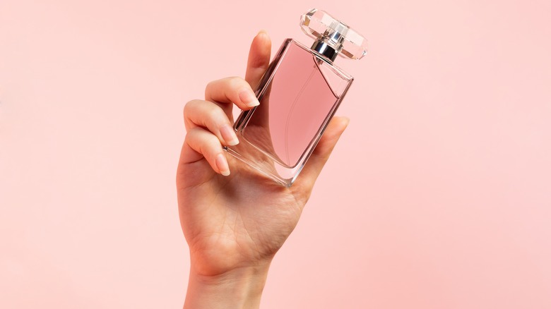 woman holding pink perfume bottle