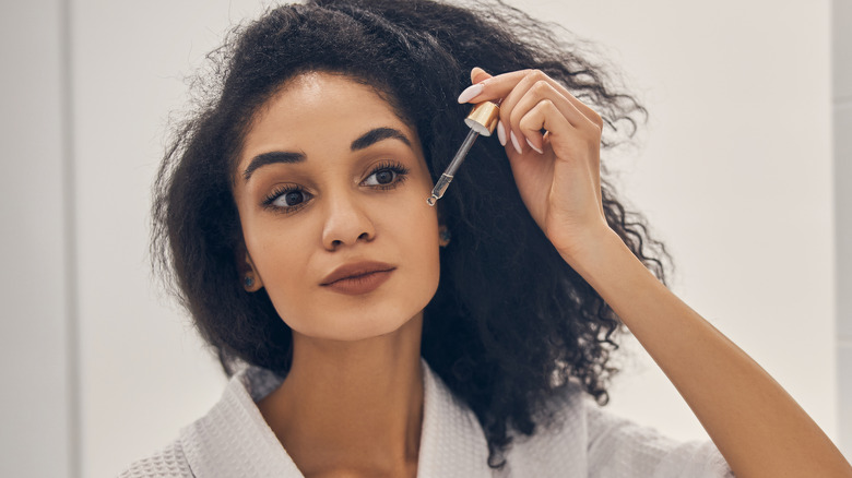 Woman applying serum to her face