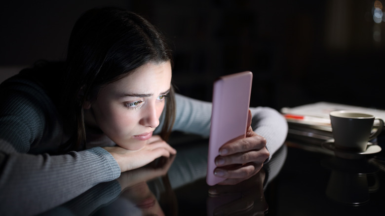 Sad woman glaring at her phone 