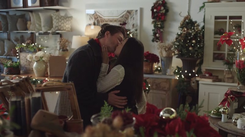 Janel Parrish and Daniel Lissing kissing in a room decorated for Christmas