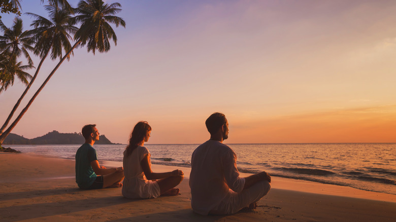 Young people meditating on beach