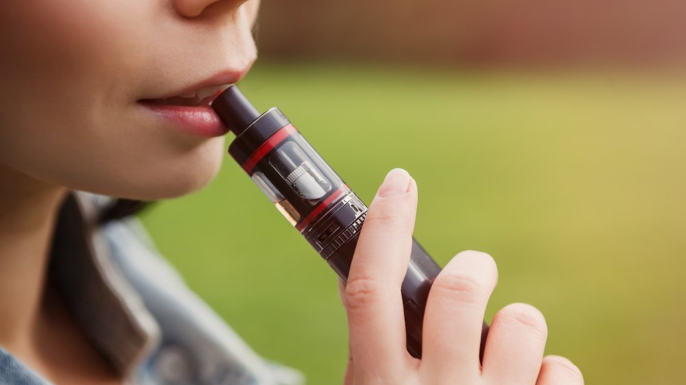 A woman with her mouth on a vape pen