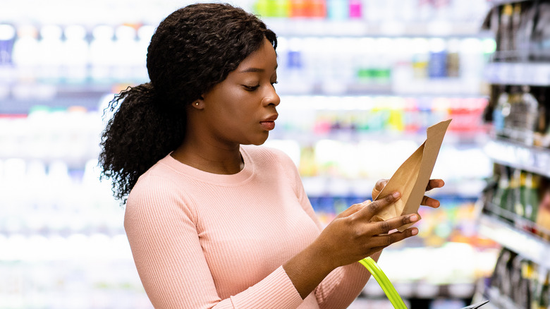 Woman reading food label in store