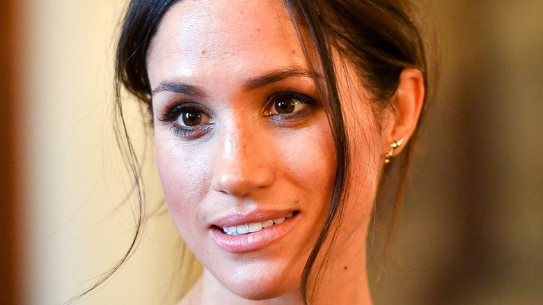 Meghan Markle smiling while holding a copy of her book 