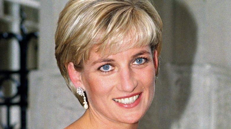 Princess Diana smiling at the camera wearing pearl drop earrings