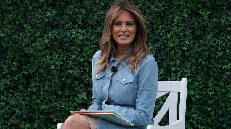 Melania Trump smiling with a book on her lap