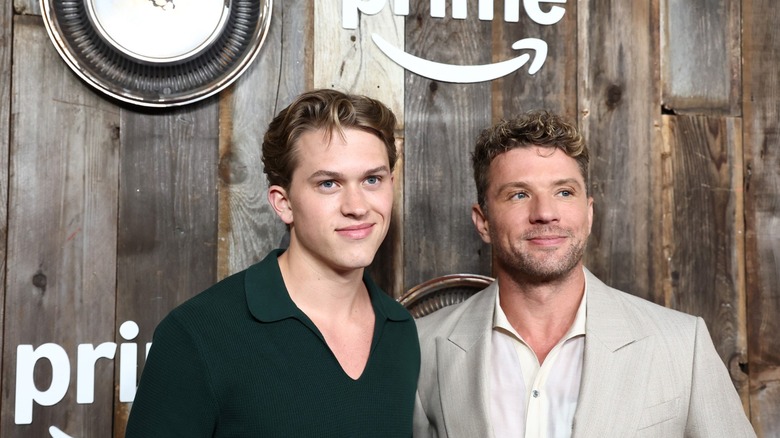 Ryan Phillippe and Deacon Phillippe in front of a wood-paneled wall with Prime logos and car parts