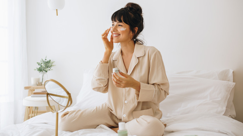 A woman putting cream on her face