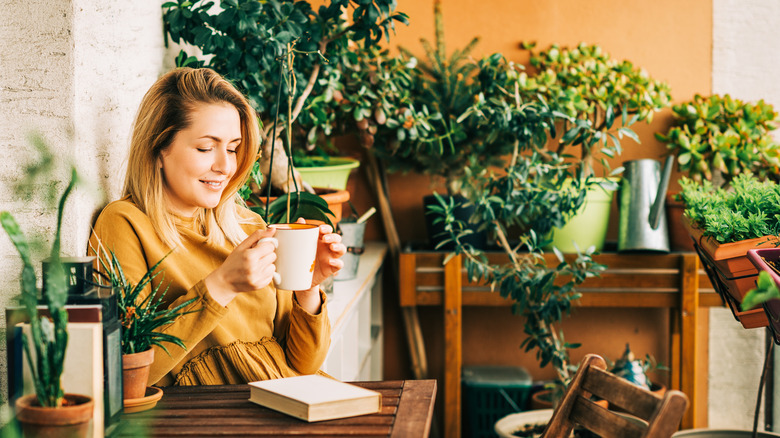 Woman with tea by indoor plants