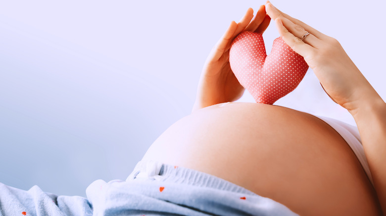 pregnant woman holding heart pillow