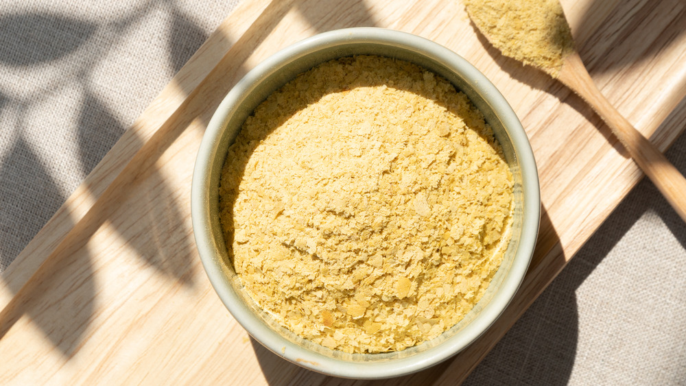 Nutritional yeast in a bowl with a wooden spoon